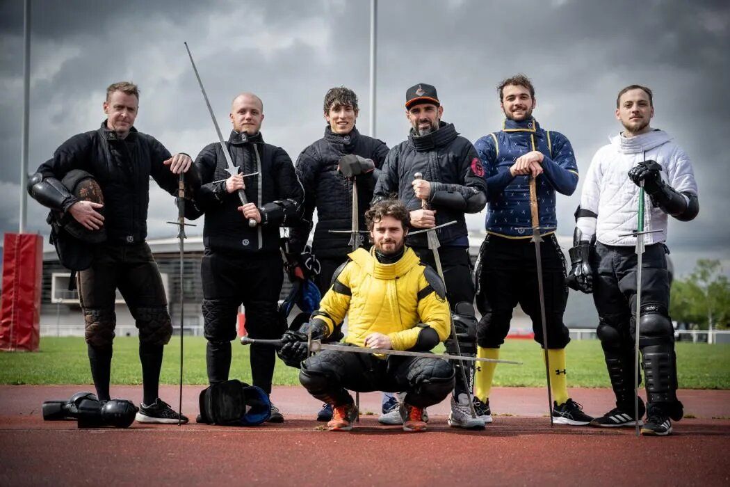 Sept membres du club posent sur une piste d'athlétisme avec leurs épées longues.